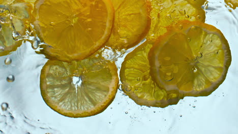 trozos de naranjas salpicando líquido de cerca. rebanadas de cítricos flotando bajo el agua