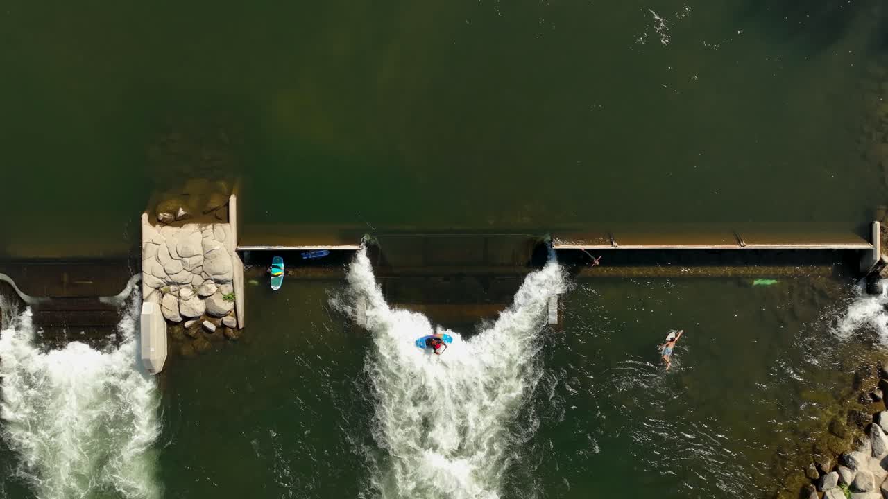 Overhead aerial of reservoir spillway with kayaker paddling in whitewater rapids