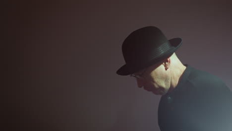 mysterious silhouette of a man in a black hat and glasses, shadowed against a softly blurred background