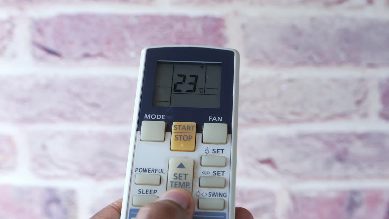 Hand holding an air conditioner remote control