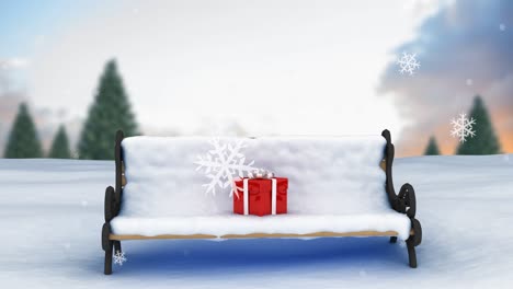 Animation-Von-Schnee,-Der-über-Ein-Weihnachtsgeschenk-Auf-Eine-Schneebedeckte-Bank-In-Einer-Winterlandschaft-Fällt