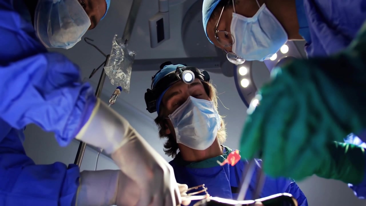 Paziente sdraiato sul tavolo, team medico che estrae tessuto per l'ispezione, facendo apparire icone di pollice in su.