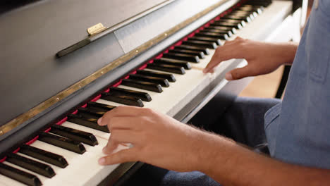 sección media de un hombre biracial tocando el piano en casa, en cámara lenta