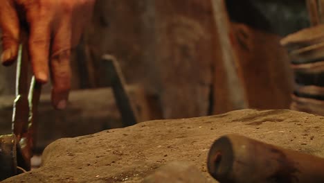 blacksmith picking up hot metal bowls with tongs, close up