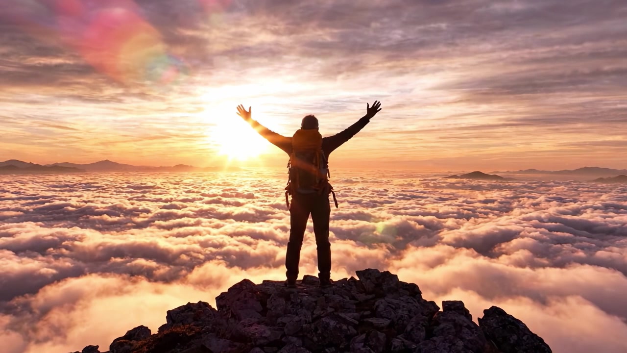 Un excursionista contempla el hermoso amanecer sobre las nubes, de pie en la cima de una montaña rodeado por un vasto mar de niebla que se eleva bajo un cielo colorido.