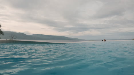 Ondas-De-Agua-En-La-Superficie-De-Una-Piscina-Infinita-Cielo-Nublado-Puesta-De-Sol