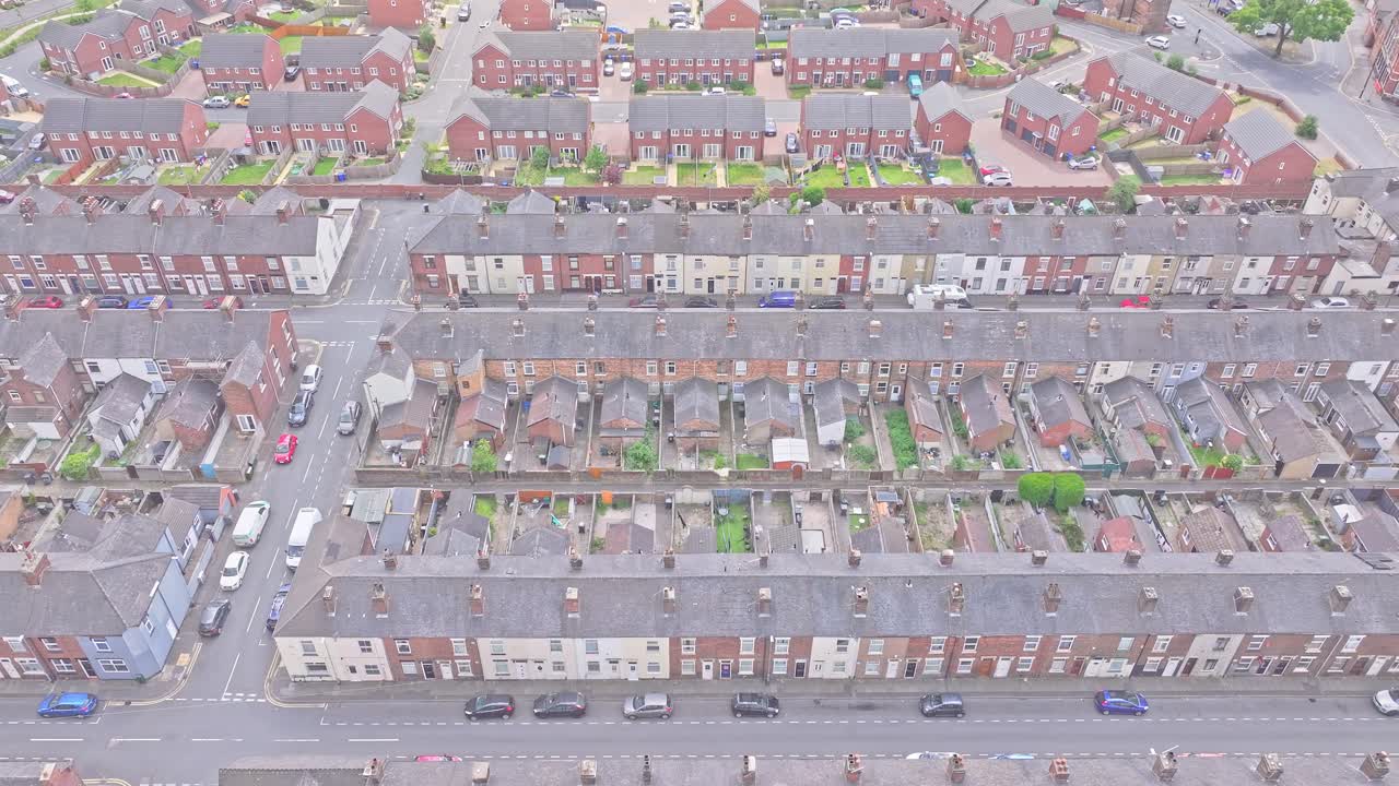 Descending drone view of terraced housing in Stoke-on-Trent, England, showing grid-pattern streets and uniform rooftops in a densely built residential zone