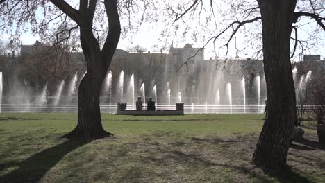 people relaxing by a fountain in a city park