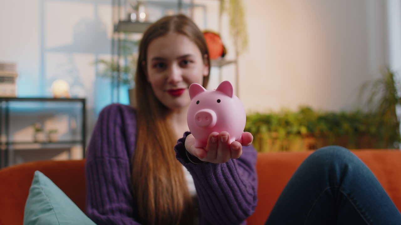 Young woman holding piggybank and putting in one dollar banknote save money investment economy