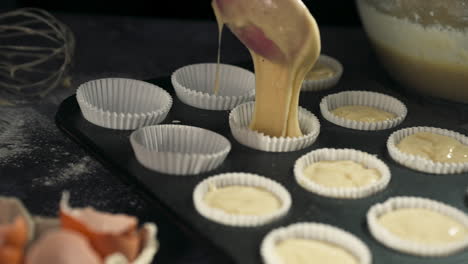 delicate ladle is used to fill liners preparing cupcakes for baking in the oven during the dessert preparation process