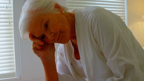 front view of caucasian worried senior woman relaxing on bed in a comfortable home 4k