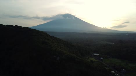 mount agung backlit at sunset with mist and clouds, amed bali indonesia, aerial dolly