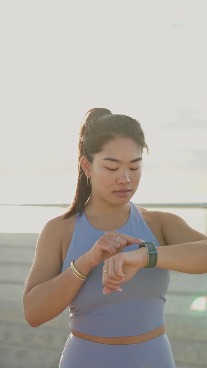 Young Woman Checking Fitness Tracker on Smartwatch Outdoors