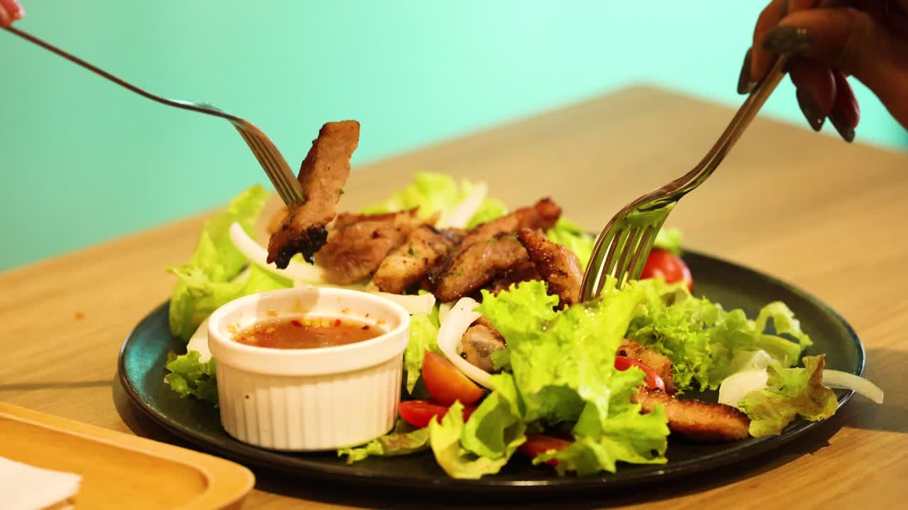 horquillas recogiendo carne de cerdo a la parrilla del plato de ensalada