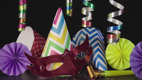 party hats, carnival mask and colorful decorations on black background