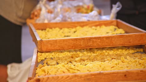 orecchiettepasta tradicional hecha a mano fresca que se seca en estantes y bandejas en la calle de bari italia mientras las mujeres y los clientes hablan en el fondo, tiro brillante, cálido y estático
