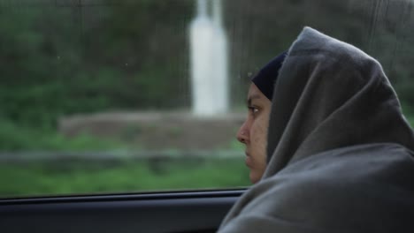 Junge-Muslimische-Frauen,-Die-In-Nachdenklicher-Pose-Mit-Schal-über-Ihrem-Hijab-Aus-Dem-Autofenster-Schauen