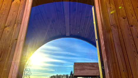 un sol que pasa en un cielo azul visto a través de una gran ventana