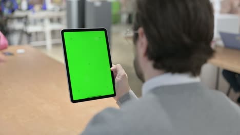 hombre mirando una tableta con pantalla de croma verde