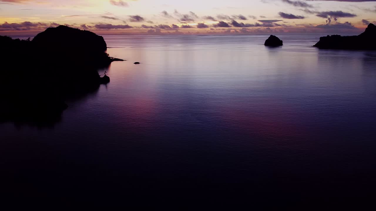 Silhouette Image Of Mountains On A Calm Sea With Cloudy Sky At The Background