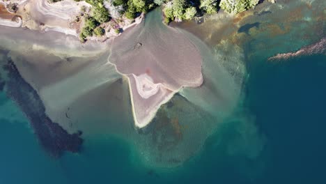 Island-forming-of-mud-in-blue-lake-because-of-river,-aerial-view