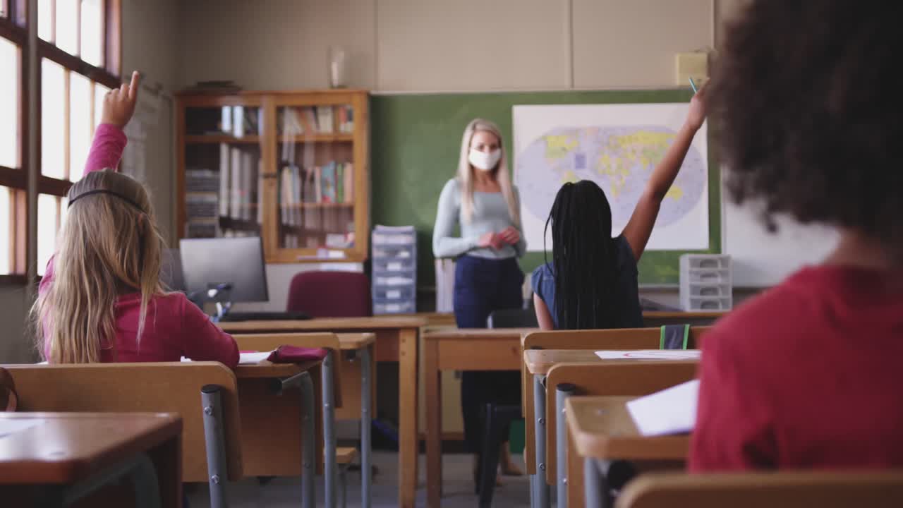 grupo de niños levantando las manos en la clase en la escuela