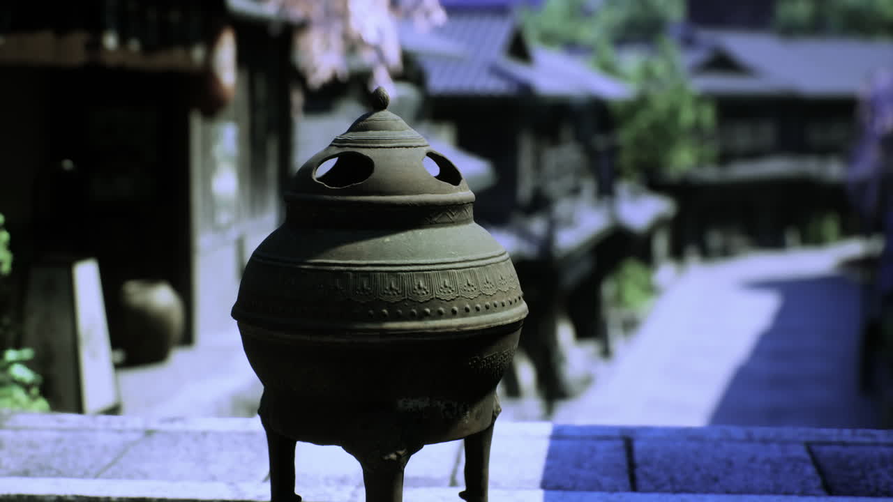A detailed bronze incense burner is placed prominently in a serene street