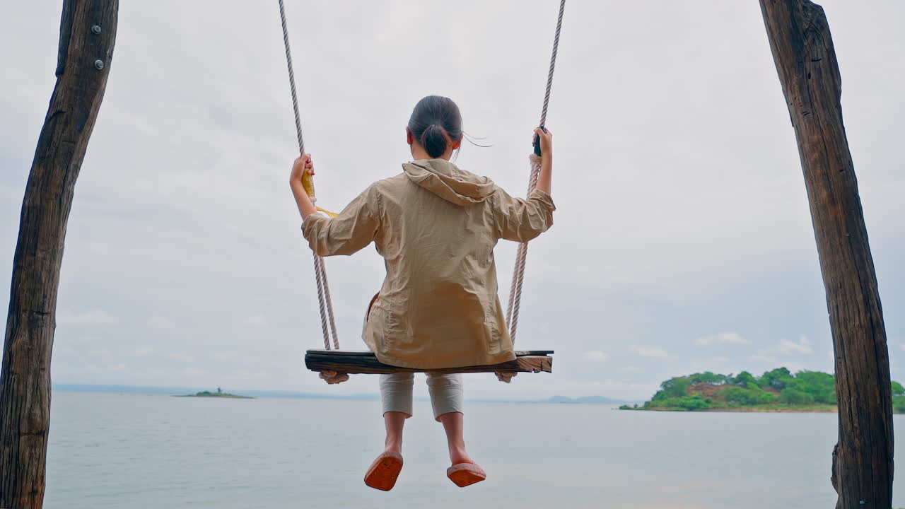 소녀는 여름 저녁 바다 해변 근처에서 그네를 타고 비행을 즐깁니다.