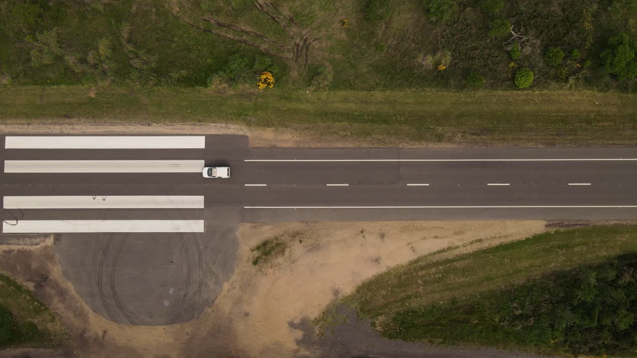 toma aérea de arriba hacia abajo de la conducción de automóviles en la carretera de la pista de aterrizaje de emergencia en uruguay