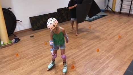 girl learning to roller skate in a gym