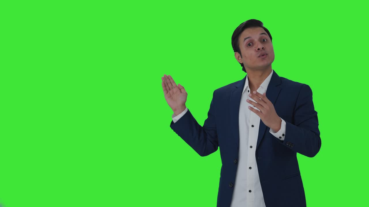 Giornalista indiana felice che indica spazio per il testo e parla su schermo verde