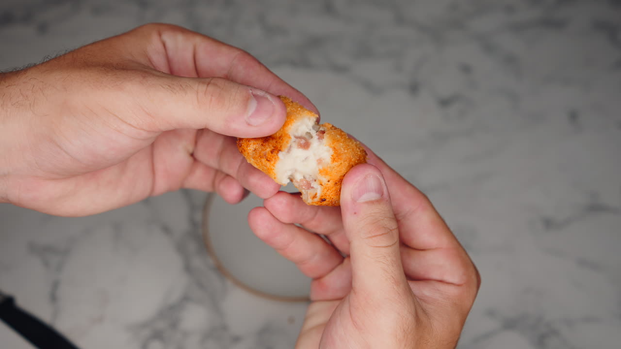 Close up of a person breaking apart a croquette