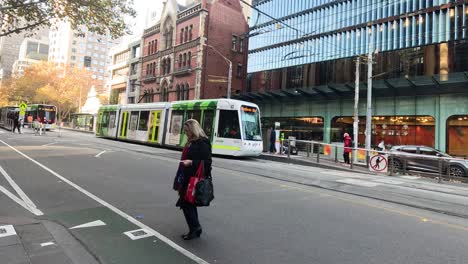 people crossing street with tram and cars