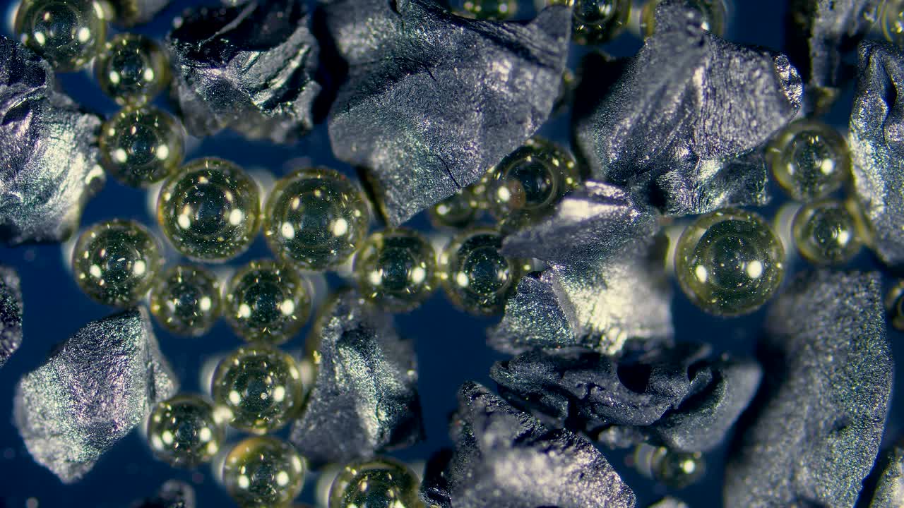Ion-exchange resin beads in water filter between activated charcoal granules under microscope