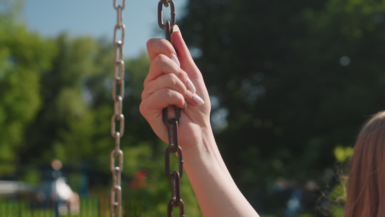 아이가 그네를 잡는다. 화창한 공원에서 그네를 꽉 쥐고 있는 어린아이. 밝은 가족 나들이 중 그네 체인을 잡고 있는 아이. 쾌적한 여름날 공원에서 그네 체인을 잡고 있는 어린아이