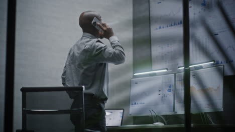 stock exchange broker shouting in phone, soaking financial loss, monitoring real-time stocks, exchange market charts in office at night. african american investment agent angry about bad economy news.
