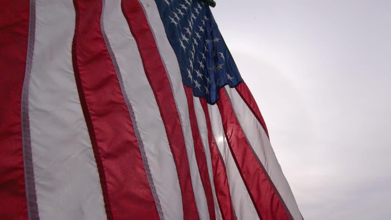 Bandiera americana 4K che sventola lentamente con una dolce brezza, rossa, bianca e blu, stelle e strisce patriottiche retroilluminate. B-roll di giorno