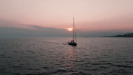 small boat sailing at the edge of italian coast during sunset - wide shot