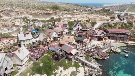 Low-level-orbit-aerial-shot-of-Mediterranean-Anchor-Bay-overlooking-Popeye-Village,-Malta