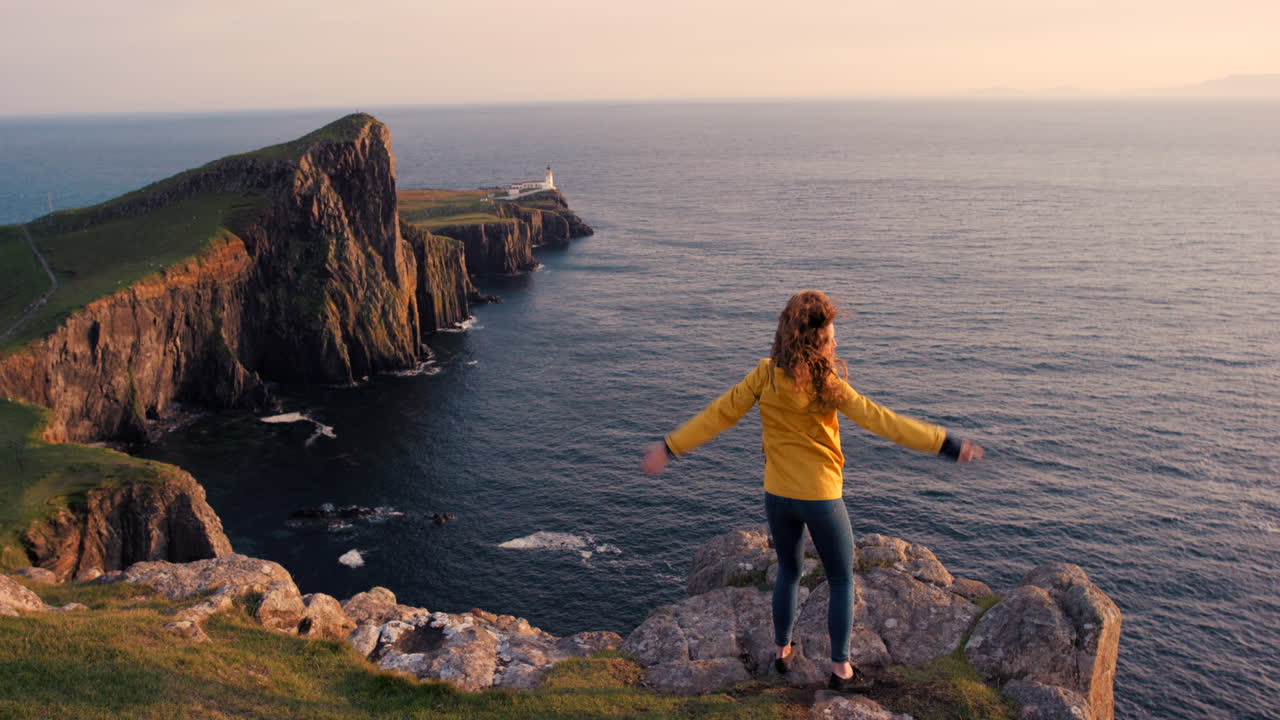 mujer disfrutando de la vista del atardecer desde un acantilado en escocia