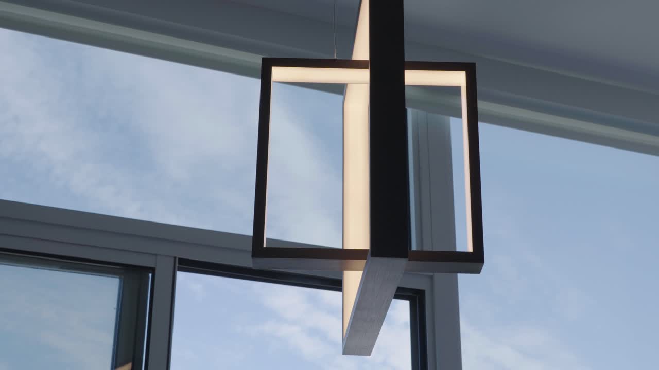 Close up dolly detail shot of a contemporary pendant lamp with ceiling high window at the back in a condominium during a sunny day
