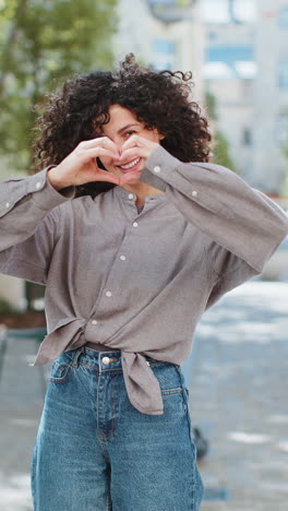 young woman makes symbol of love, showing heart sign to camera, express romantic positive feelings