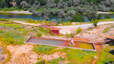 antena de una niña con un vestido largo parada en un depósito de agua de concreto cerca de una mina abandonada y el río arda