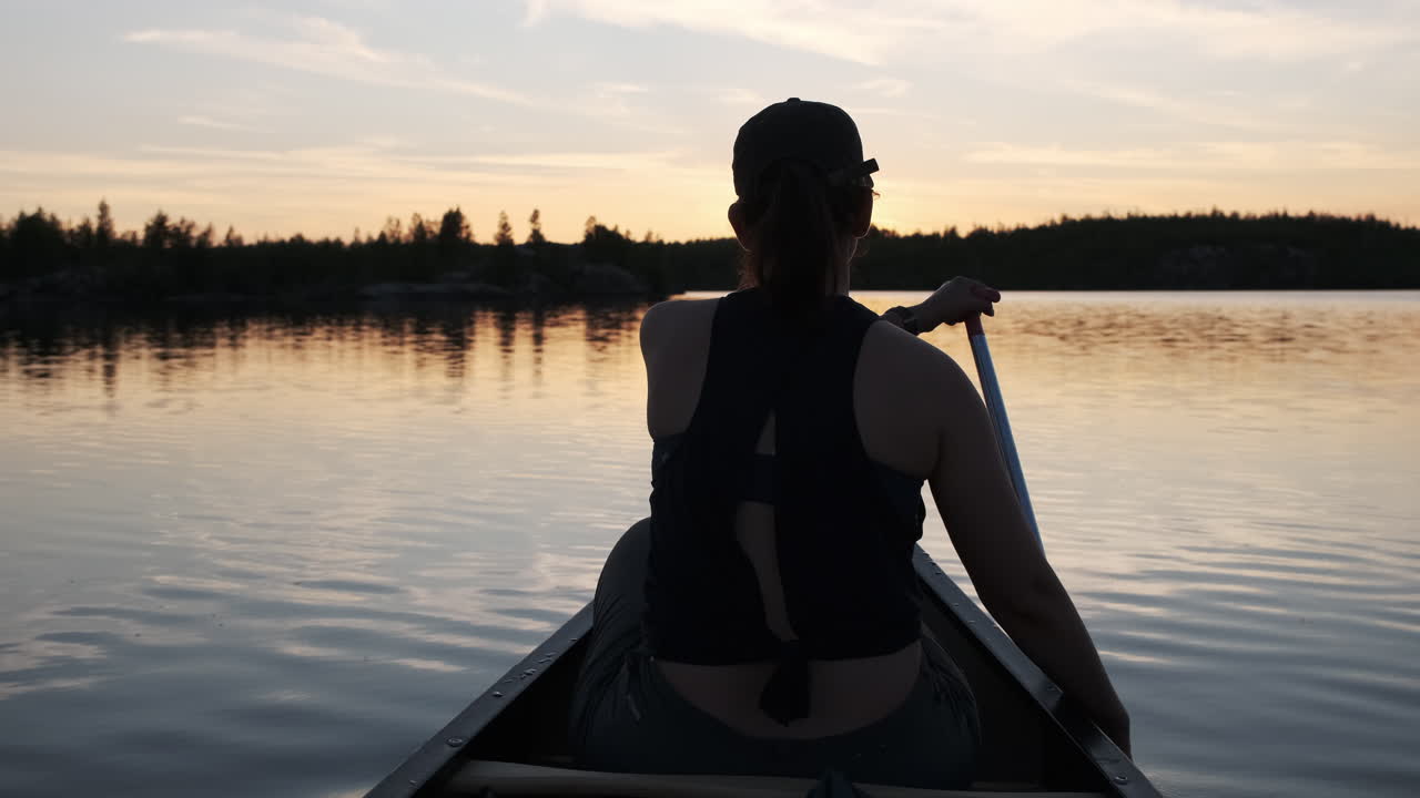 mujer remando una canoa en hermosos reflejos de puesta de sol en las aguas fronterizas