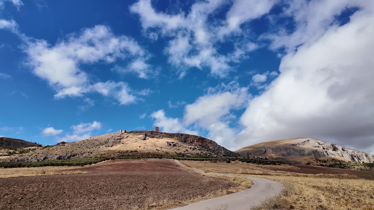Toma estática en tiempo real del Castillo de la Estrella en España, mostrando nubes moviéndose por el cielo y hierba meciéndose con el viento en un día soleado.