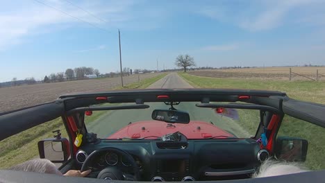 pov while a couple are driving on a country road with roof off of their vehicle