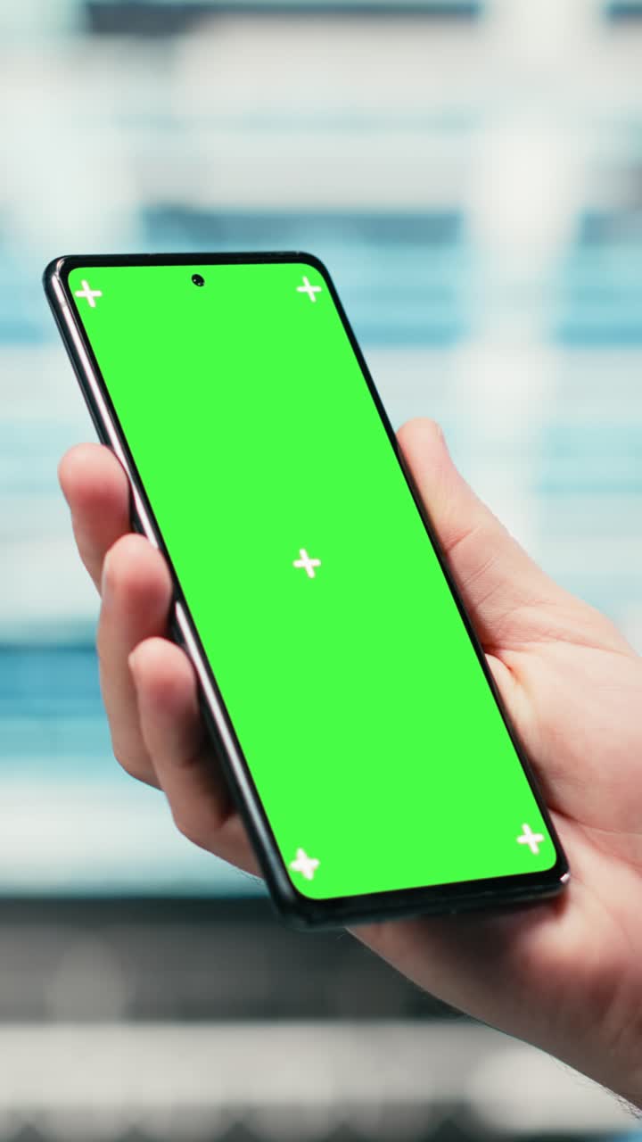 Video verticale: smartphone con green screen utilizzato da un amministratore di data center per gestire l'attrezzatura a rete wireframe.