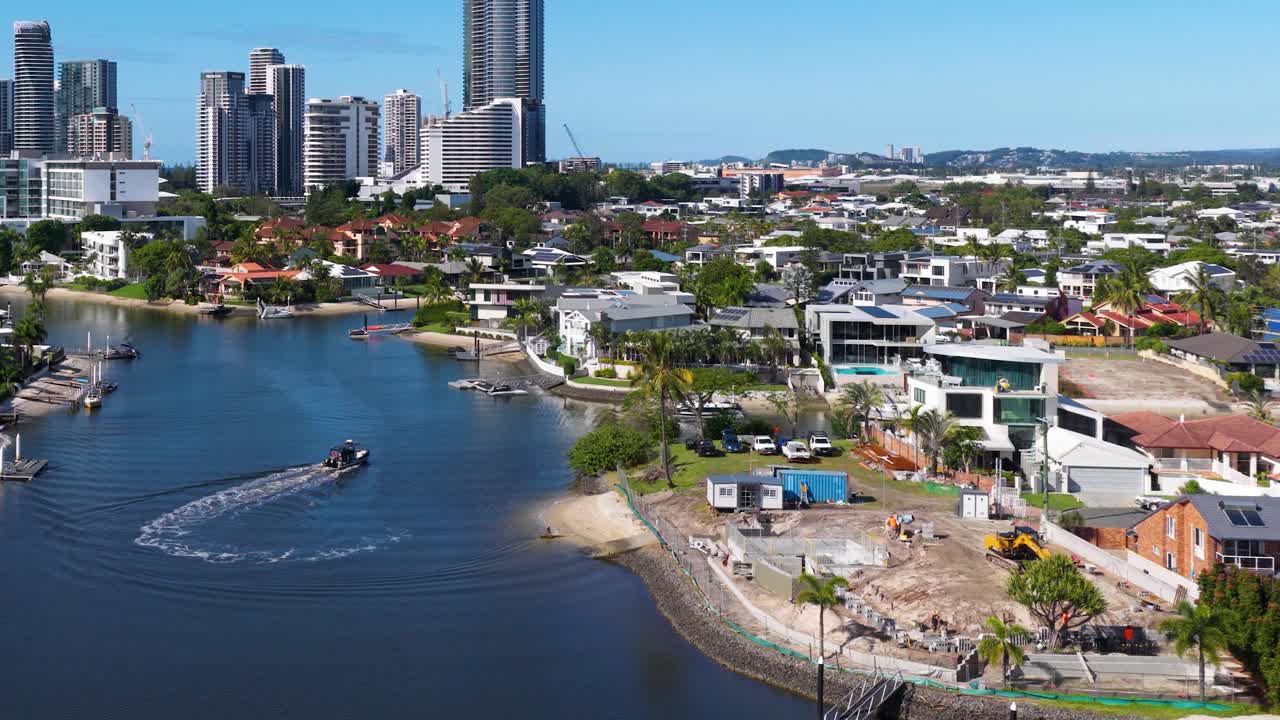 Aerial footage of a boat navigating a scenic waterway in Gold Coast, Australia, with urban skyline and clear skies