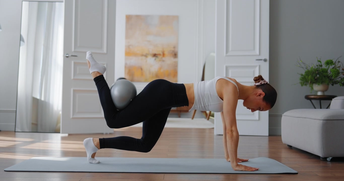 Fit Woman Performing Plank Exercise with Stability Ball at Home