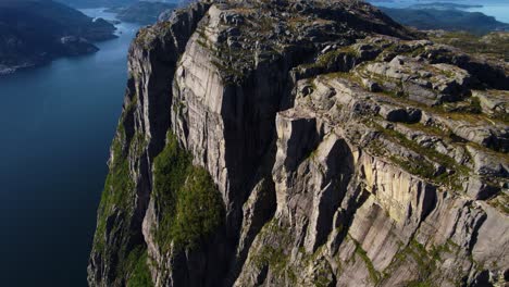 majestic view of preikestolen pulpit rock, norway. surrounded by fjord water and mountain terrain.